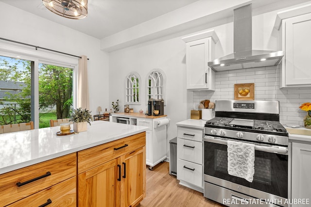 392 Harbor Town Ct Unit 2, Holland, MI 49423 - kitchen with gas range, wall chimney range hood, light countertops, decorative backsplash, and light wood-style floors
