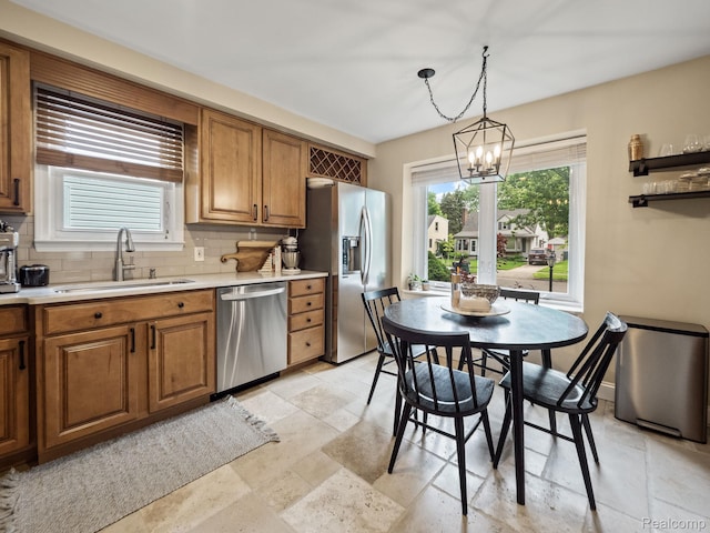 1017 N Connecticut Ave, Royal Oak, MI 48067 - kitchen featuring appliances with stainless steel finishes, a sink, brown cabinetry, a chandelier, and stone tile floors
