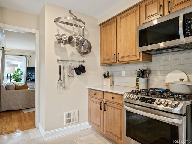 1017 N Connecticut Ave, Royal Oak, MI 48067 - kitchen featuring stainless steel appliances, backsplash, light countertops, baseboards, and brown cabinetry