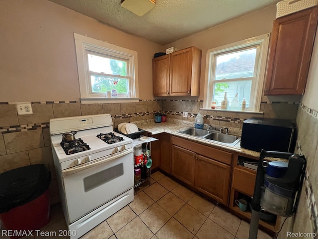 6101 Auburn St, Detroit, MI 48228 - kitchen featuring white range with gas cooktop, a sink, light tile patterned flooring, light countertops, and a textured ceiling