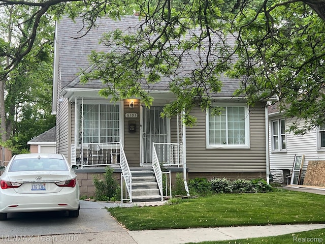 6101 Auburn St, Detroit, MI 48228 - view of front of house with roof with shingles, covered porch, and a front lawn