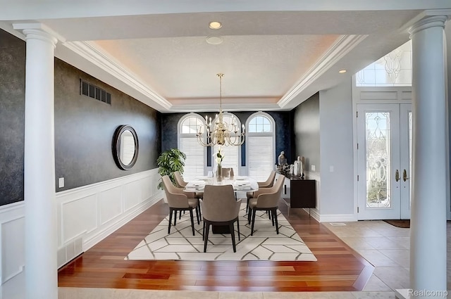 2571 N Long Lake Rd, Fenton, MI 48430 - dining room with ornate columns, wood finished floors, a chandelier, a tray ceiling, and a decorative wall