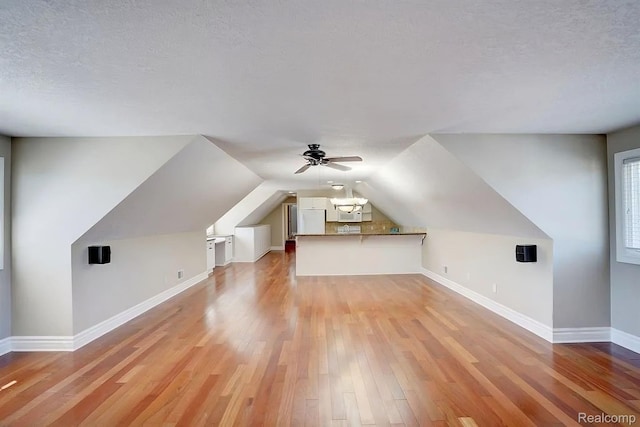 2571 N Long Lake Rd, Fenton, MI 48430 - additional living space with light wood finished floors, baseboards, ceiling fan, vaulted ceiling, and a textured ceiling