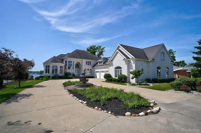 2571 N Long Lake Rd, Fenton, MI 48430 - french country home featuring curved driveway, an attached garage, and stucco siding
