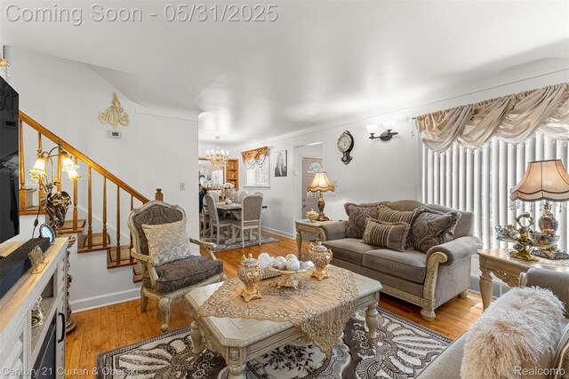 15210 Russell Ave, Allen Park, MI 48101 - living room with a chandelier, stairway, light wood finished floors, and baseboards