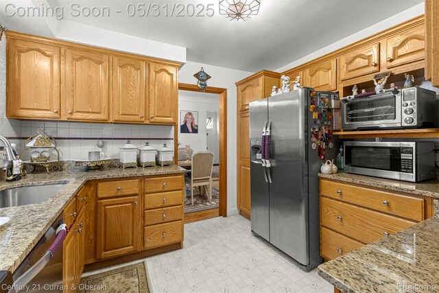 15210 Russell Ave, Allen Park, MI 48101 - kitchen featuring stainless steel appliances, a sink, light stone counters, backsplash, and brown cabinetry