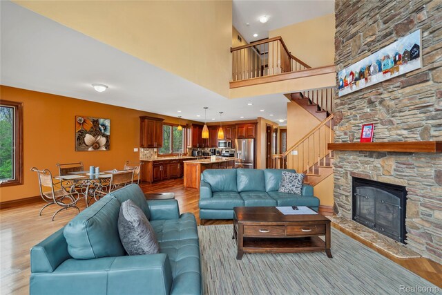 11589 Ember, Davisburg, MI 48350 - living area with light wood-style flooring, stairway, a stone fireplace, and a towering ceiling
