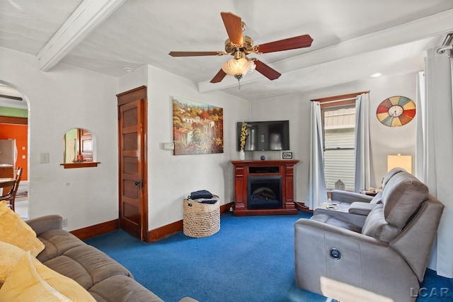 134 W Lagrange St, Morenci, MI 49256 - carpeted living room with beam ceiling, baseboards, ceiling fan, arched walkways, and a fireplace with raised hearth
