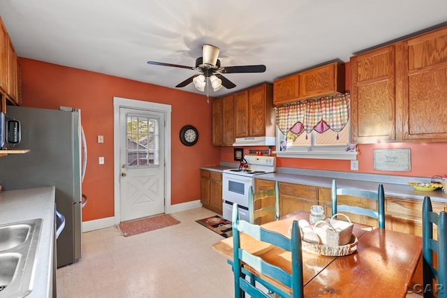 134 W Lagrange St, Morenci, MI 49256 - kitchen with white electric range, ceiling fan, under cabinet range hood, brown cabinets, and light floors