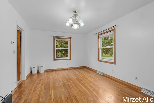 1145 Eastmont Dr SE, Grand Rapids, MI 49546 - spare room featuring healthy amount of natural light, a chandelier, and light wood-type flooring