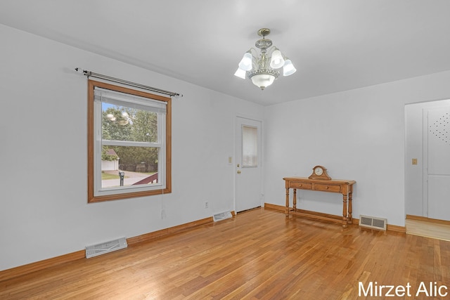 1145 Eastmont Dr SE, Grand Rapids, MI 49546 - empty room with light wood-type flooring, a chandelier, and baseboards