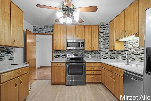 1145 Eastmont Dr SE, Grand Rapids, MI 49546 - kitchen with stainless steel appliances, ceiling fan, a sink, backsplash, and light wood-type flooring