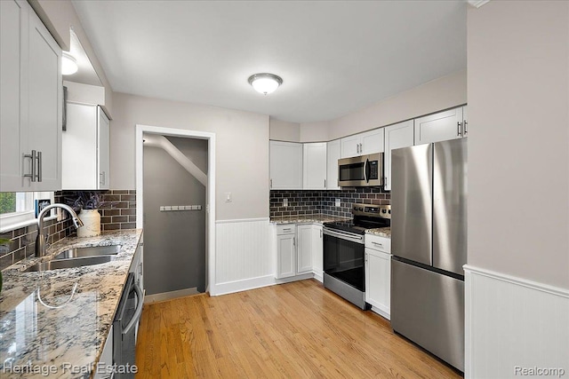 2376 Bacon Ave, Berkley, MI 48072 - kitchen featuring appliances with stainless steel finishes, a sink, light wood-style floors, light stone countertops, and backsplash