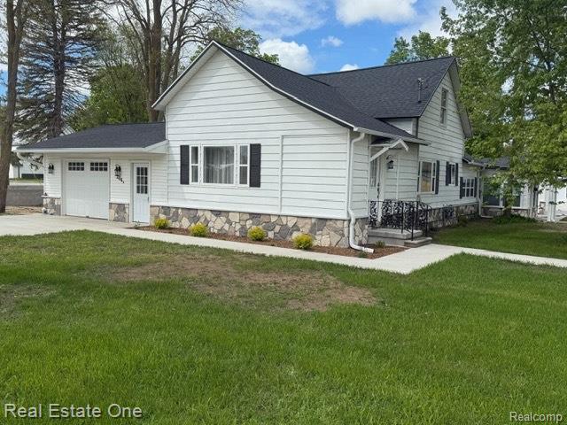 206 W 4th St, Kalkaska, MI 49646 - view of front of property featuring a garage, a front yard, and driveway