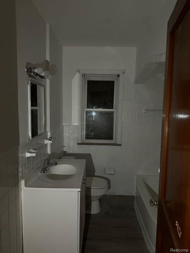 13801 Fordham St, Detroit, MI 48205 - bathroom with tile walls, vanity, a bath, toilet, and wood finished floors