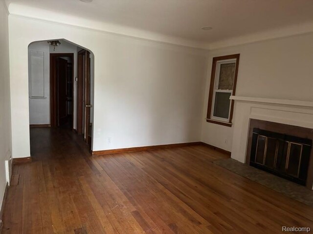 13801 Fordham St, Detroit, MI 48205 - unfurnished living room featuring hardwood / wood-style floors, arched walkways, a fireplace with flush hearth, and baseboards