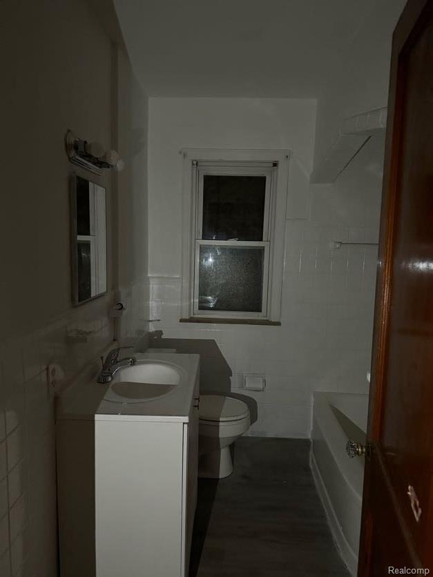 13801 Fordham St, Detroit, MI 48205 - full bath with tile walls, vanity, toilet, a tub to relax in, and wood finished floors