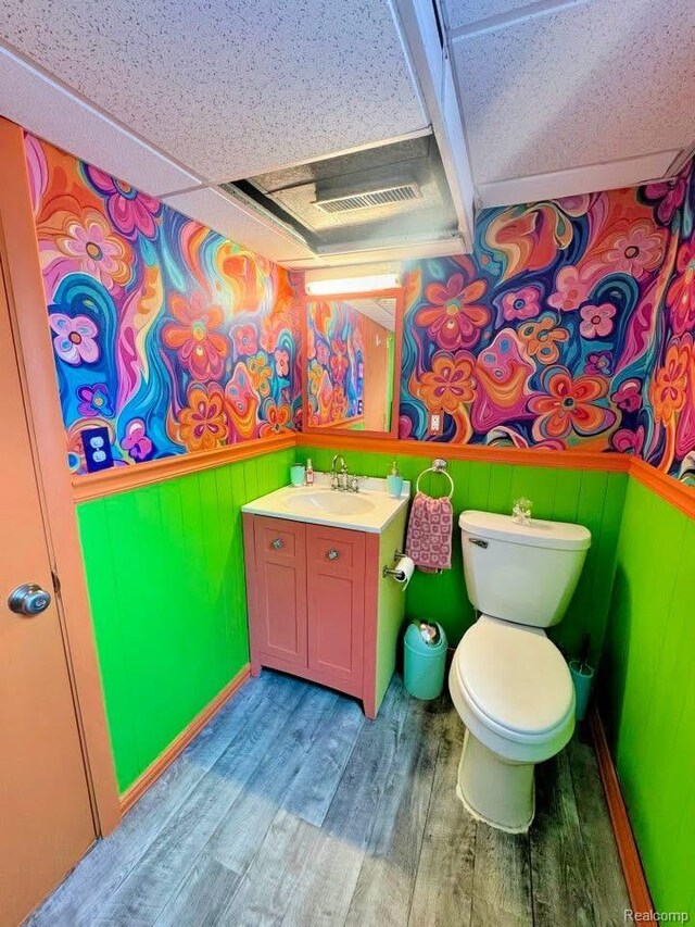 219 W Butler St, Bad Axe, MI 48413 - half bathroom with wood finished floors, vanity, toilet, and a wainscoted wall