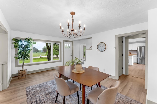 5853 W 112th St, Grant, MI 49327 - dining room with light wood-type flooring, a chandelier, baseboards, and a textured ceiling
