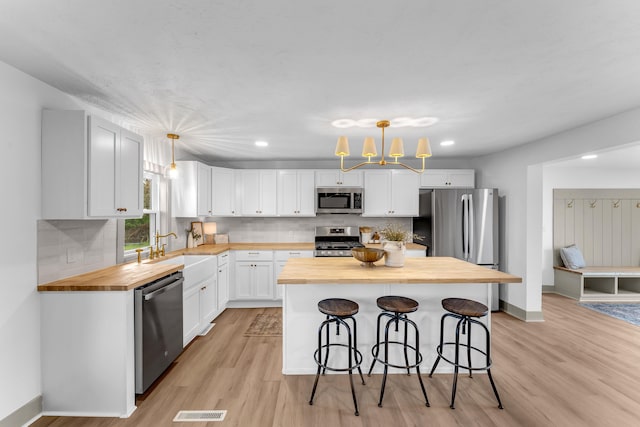 5853 W 112th St, Grant, MI 49327 - kitchen featuring butcher block countertops, stainless steel appliances, a sink, white cabinets, and recessed lighting