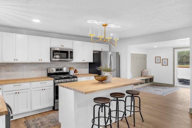 5853 W 112th St, Grant, MI 49327 - kitchen featuring butcher block countertops, appliances with stainless steel finishes, a kitchen breakfast bar, light wood-style floors, and recessed lighting
