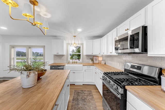 5853 W 112th St, Grant, MI 49327 - kitchen with butcher block counters, stainless steel appliances, light wood-type flooring, a chandelier, and white cabinetry
