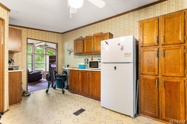 1211 107th Ave, Otsego, MI 49078 - kitchen featuring white appliances, a ceiling fan, ornamental molding, brown cabinets, and wallpapered walls