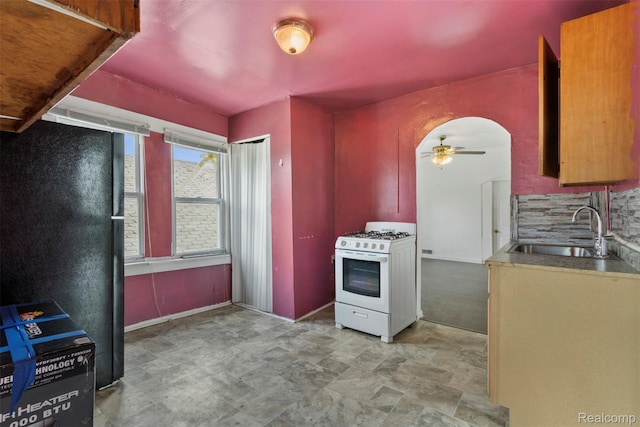 5151 Yemans St, Hamtramck, MI 48212 - kitchen with white range with gas stovetop, a sink, ceiling fan, decorative backsplash, and freestanding refrigerator