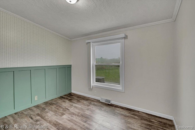5951 English Rd, Silverwood, MI 48760 - spare room featuring crown molding, wood finished floors, a textured ceiling, a wainscoted wall, and a decorative wall