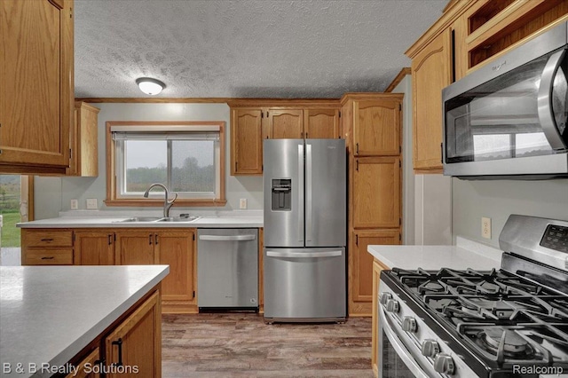5951 English Rd, Silverwood, MI 48760 - kitchen with appliances with stainless steel finishes, a sink, light wood-style floors, light countertops, and a textured ceiling
