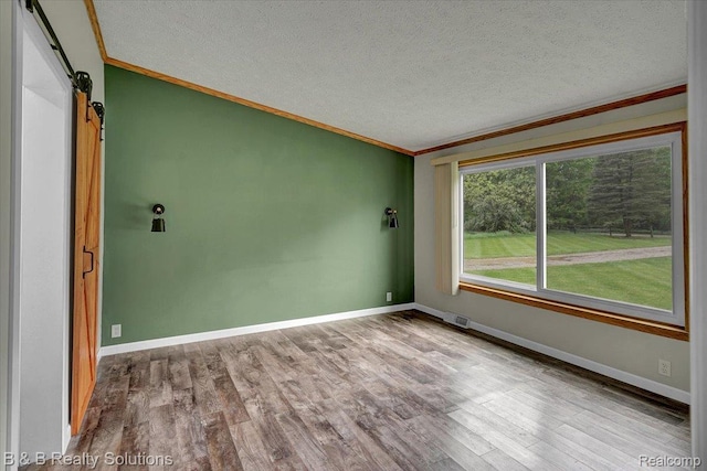 5951 English Rd, Silverwood, MI 48760 - empty room featuring crown molding, a barn door, a textured ceiling, wood finished floors, and baseboards
