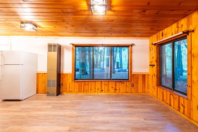 17341 Old Logging Rd, Hersey, MI 49639 - empty room featuring wood walls, a heating unit, wooden ceiling, a wainscoted wall, and light wood-style flooring