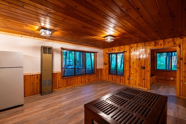 17341 Old Logging Rd, Hersey, MI 49639 - unfurnished living room featuring wood walls, wood ceiling, wood finished floors, wainscoting, and a heating unit
