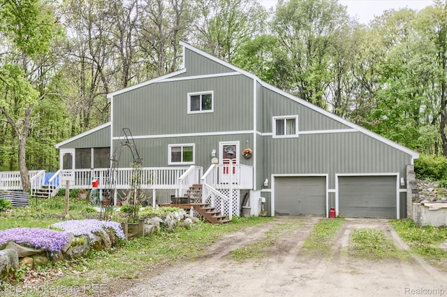 12445 Shaffer Rd, Davisburg, MI 48350 - view of front facade featuring dirt driveway, a garage, a sunroom, view of scattered trees, and a wooden deck