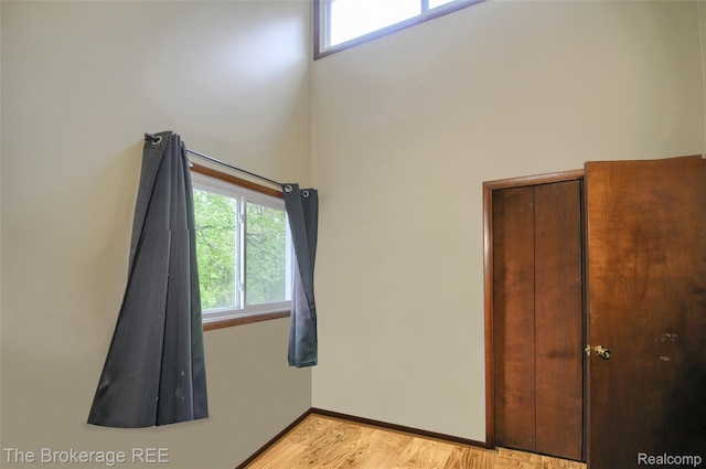 12445 Shaffer Rd, Davisburg, MI 48350 - unfurnished bedroom with a towering ceiling, multiple windows, light wood-style floors, and baseboards