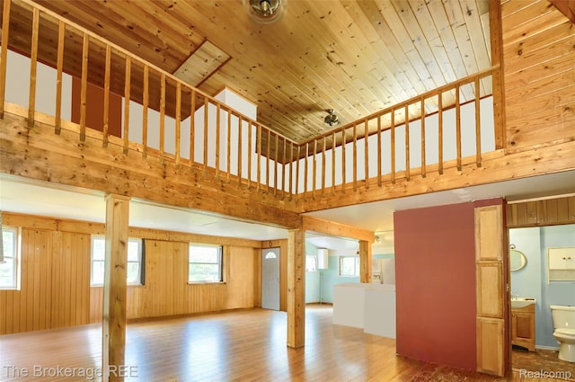 12445 Shaffer Rd, Davisburg, MI 48350 - unfurnished living room featuring wood finished floors, a towering ceiling, and wood walls
