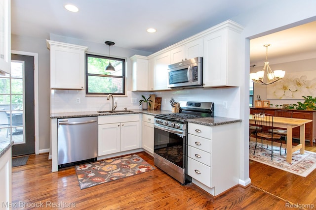 13317 Victoria Ave, Huntington Woods, MI 48070 - kitchen featuring appliances with stainless steel finishes, a sink, wood finished floors, white cabinetry, and dark stone counters