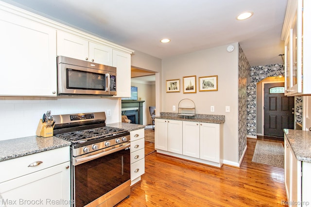 13317 Victoria Ave, Huntington Woods, MI 48070 - kitchen with stainless steel appliances, white cabinets, light wood-style flooring, light stone counters, and recessed lighting