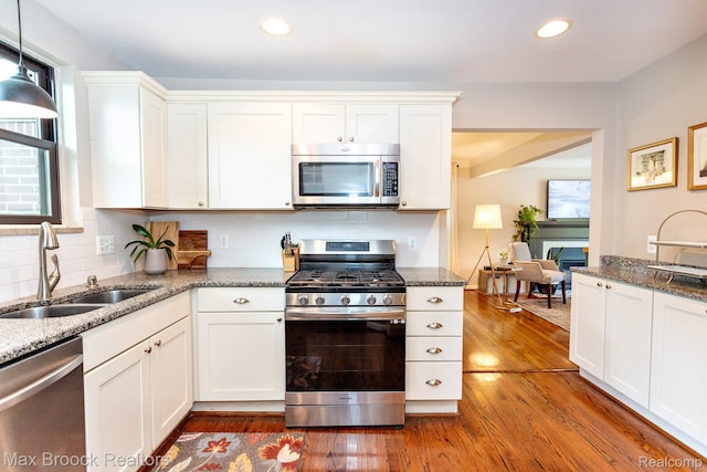 13317 Victoria Ave, Huntington Woods, MI 48070 - kitchen with stainless steel appliances, a sink, dark wood-type flooring, white cabinetry, and backsplash