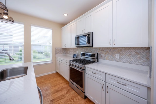 4301 Rolling Meadow Ln, Ypsilanti, MI 48197 - kitchen featuring appliances with stainless steel finishes, a sink, white cabinetry, backsplash, and light wood-style flooring