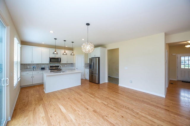 4301 Rolling Meadow Ln, Ypsilanti, MI 48197 - kitchen with appliances with stainless steel finishes, light wood finished floors, backsplash, light countertops, and an island with sink