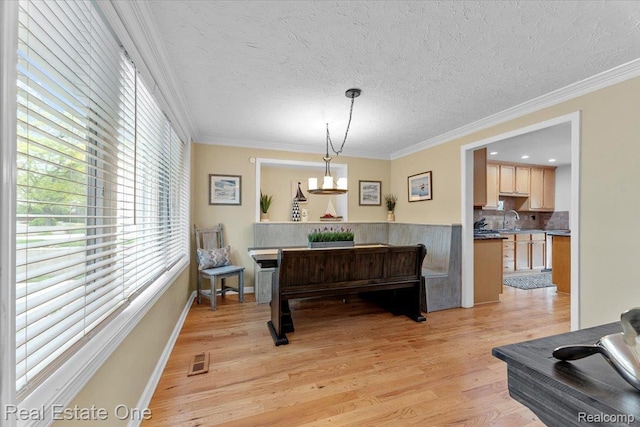 28395 Swan Island Dr, Grosse Ile, MI 48138 - dining room featuring light wood finished floors, ornamental molding, a chandelier, and a textured ceiling