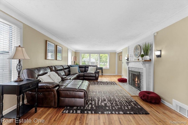 28395 Swan Island Dr, Grosse Ile, MI 48138 - living area with wood-type flooring, a fireplace, a textured ceiling, baseboards, and crown molding