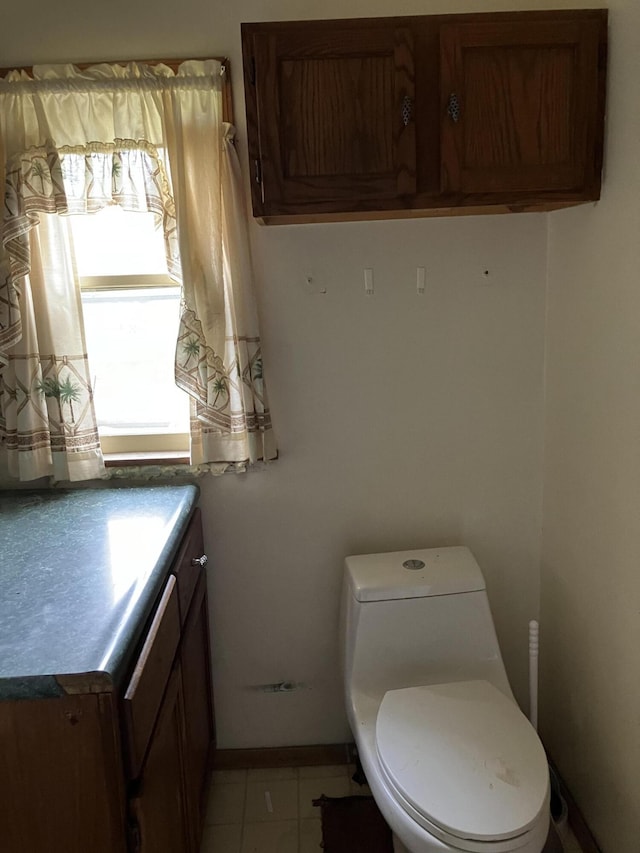 821 Fletcher St, Owosso, MI 48867 - half bathroom with vanity, toilet, tile patterned floors, and baseboards