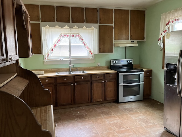 821 Fletcher St, Owosso, MI 48867 - kitchen with appliances with stainless steel finishes, under cabinet range hood, light countertops, a sink, and dark brown cabinets