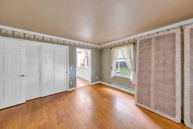 8750 20th Ave, Remus, MI 49340 - unfurnished bedroom with baseboard heating, wood finished floors, baseboards, and connected bathroom