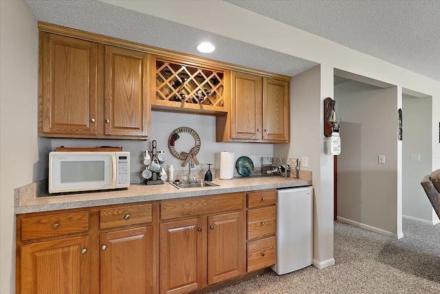 3799 Fairway Dr, Norton Shores, MI 49441 - kitchen with white microwave, fridge, light colored carpet, brown cabinets, and a textured ceiling