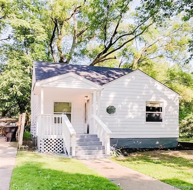 18220 Stout St, Detroit, MI 48219 - view of front facade with roof with shingles, a porch, and a front yard