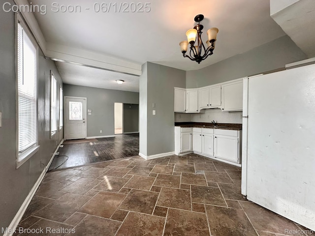 7584 Jackson Ave, Warren, MI 48091 - kitchen with dark countertops, baseboards, stone tile floors, and white cabinets