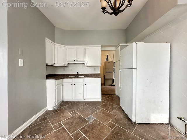 7584 Jackson Ave, Warren, MI 48091 - kitchen with freestanding refrigerator, dark countertops, a sink, stone tile floors, and white cabinetry